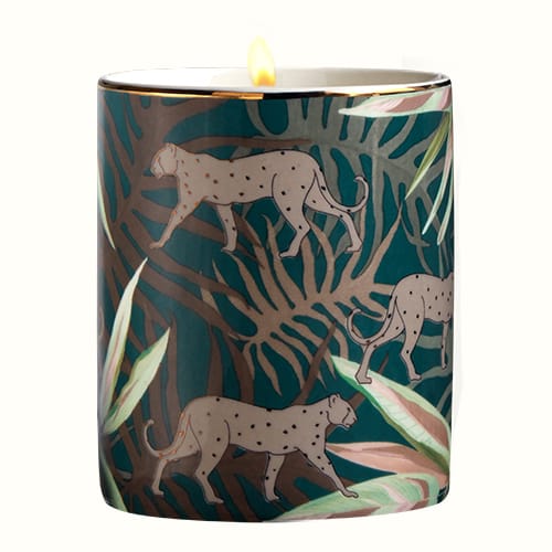 L'or de Seraphine's Ares Candle is housed in a ceramic vessel designed with golden cheetahs atop a green leaf pattern.